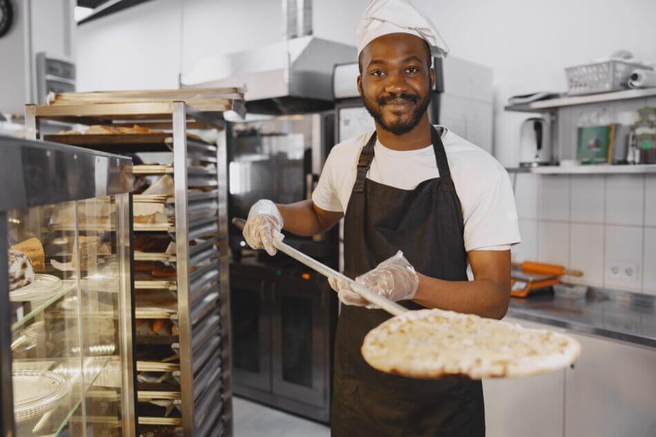 african merican man baking pizza at commercial kitchen