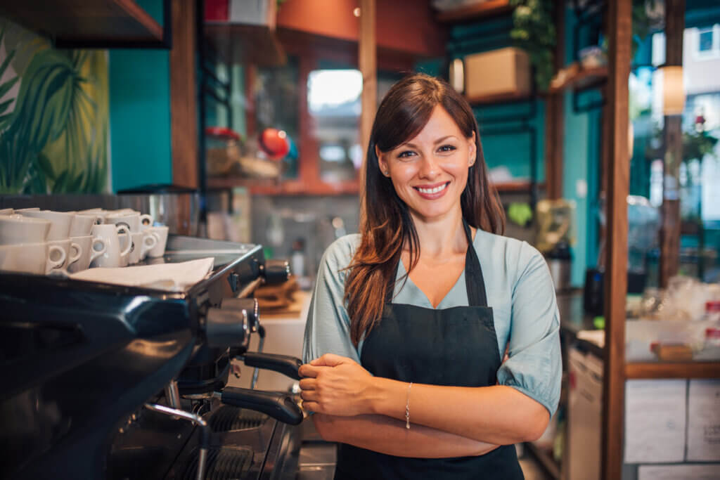 Barista souriante devant machine à café dans café